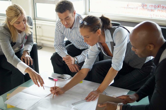 Quatre professionnels en réunion de travail analysent des documents, illustrant la collaboration entre Sofrecom et un opérateur africain pour redéfinir la gestion des carrières.