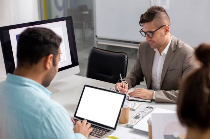 Two telecom professionals in a meeting working on MVNO strategy with laptops and digital tools.