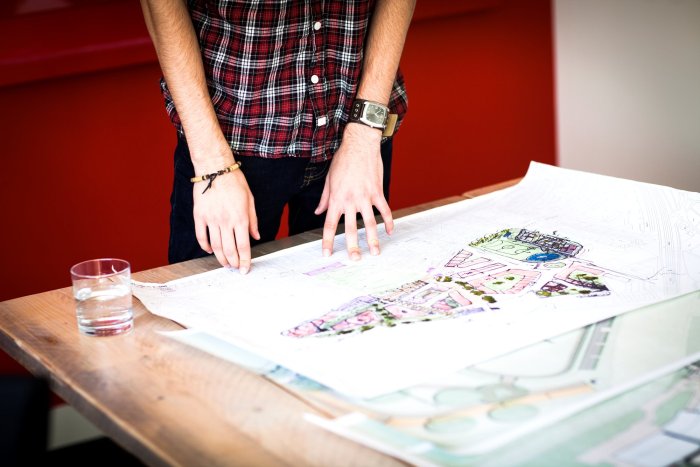 Person standing with hands on a technical plan, illustrating the planning of an information system modernization for a telecom operator.