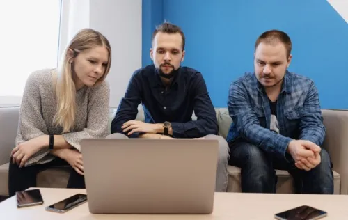 Three people consulting a laptop for the development of a mobile and web application to track traffic violations in Morocco.