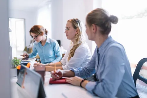Trois collaboratrices échangent dans un bureau moderne autour d’un ordinateur, illustrant la réflexion stratégique autour de l’IoT chez Sofrecom.