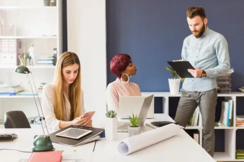 Three coworkers discussing digital strategy in a modern office, illustrating teamwork around optimizing web traffic acquisition.

