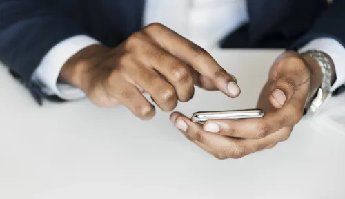 A man's hand using a smartphone, symbolizing the growing digitalization of public services.