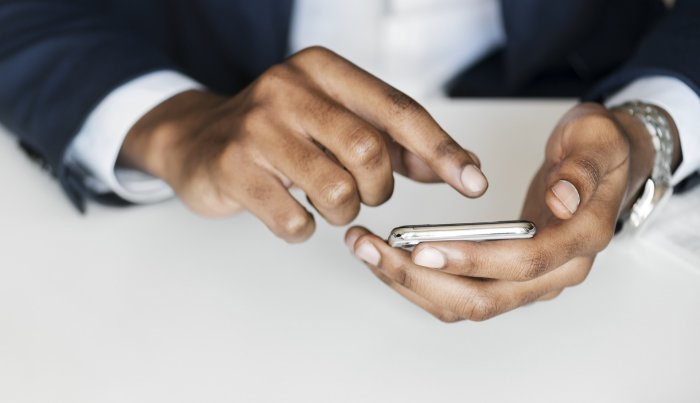 A man's hand using a smartphone, symbolizing the growing digitalization of public services.