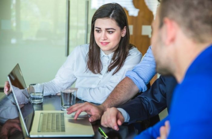 Team of telecommunications consultants analyzing an information system on a laptop during a fixed-mobile-internet integration project
