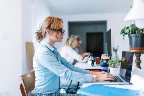 Professional women working on laptops in a modern office, symbolizing quality and expertise in IT service delivery.

