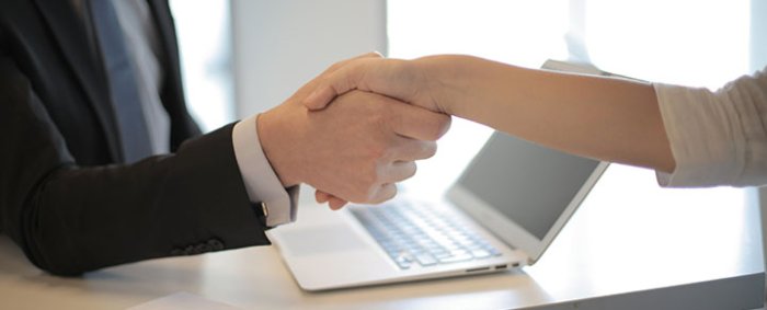 deux professionnels devant un ordinateur portable, symbolisant la confiance et la relation client au cœur de la stratégie de transformation numérique de Sofrecom.