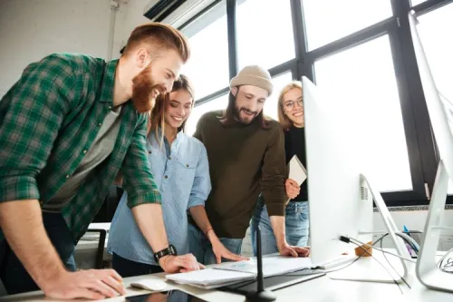 Four young professionals collaborating around a desk in a bright workspace, highlighting innovation, teamwork, and the dynamism of Tunisia’s tech job market.