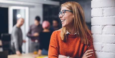 Collaboratrice souriante dans un environnement de travail en équipe, représentant la dimension humaine et collaborative d’une organisation professionnelle